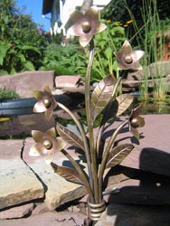 K18 Blumen aus Metall vor einem kleinen Teich