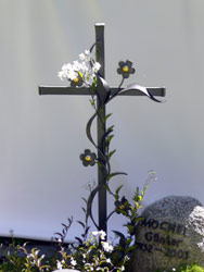 Grabstein und mit Blumen umranktes Kreuz aus Metall